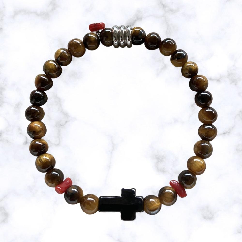 Bracelet élastique en perles Œil de Tigre aux nuances brunes mordorées. Au centre une croix noire en acier inoxydable entourée de petits morceaux de corail rouge de Méditerranée.L'œil de Tigre protège des mauvaises énergies, apporte force et courage et aide à réduire le stress.Le Corail protège, porte bonheur et éloigne le mauvais œil