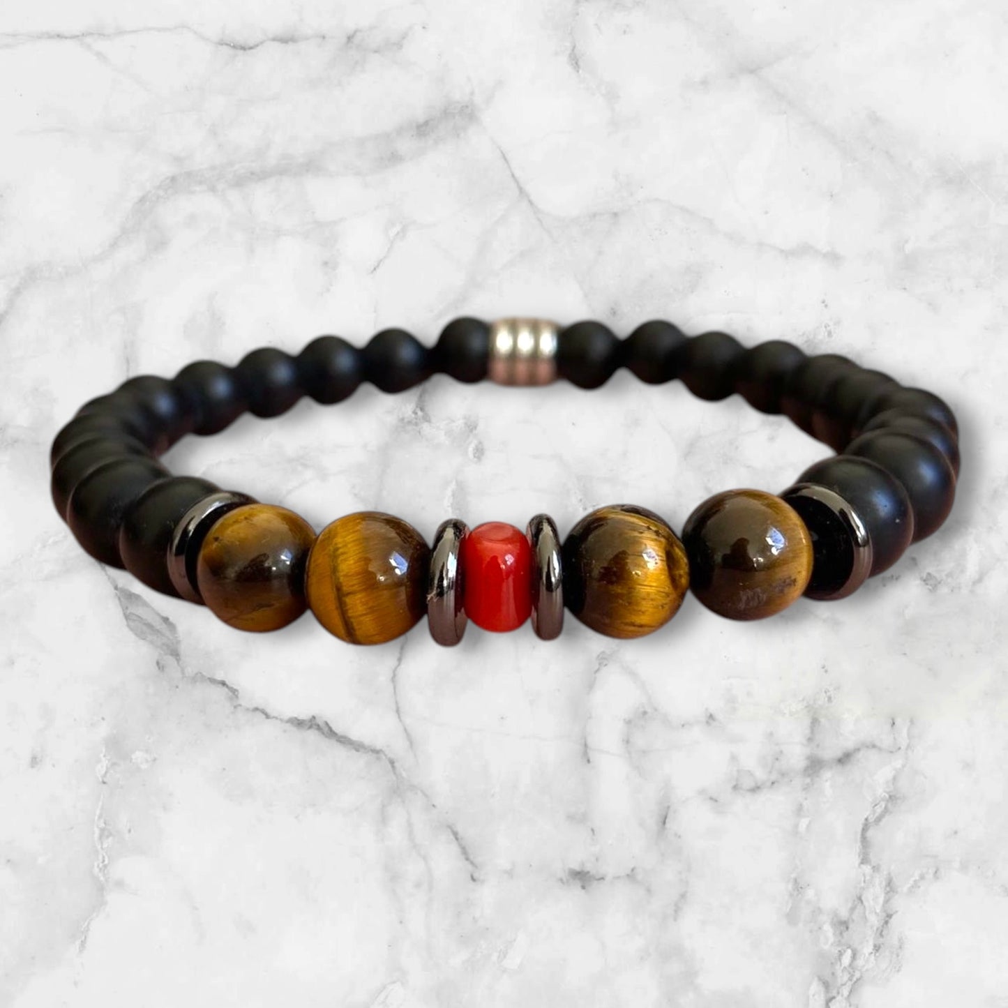 Bracelet élastique en perles d'Onyx noir mat et Œil de Tigre aux nuances brunes mordorées. Au centre un morceau de corail rouge de Méditerranée et rondelles en acier inoxydable.L'Onyx renforce l'estime de soi et la confiance en soi.L'œil de Tigre protège des mauvaises énergies, apporte force et courage et aide à réduire le stress.