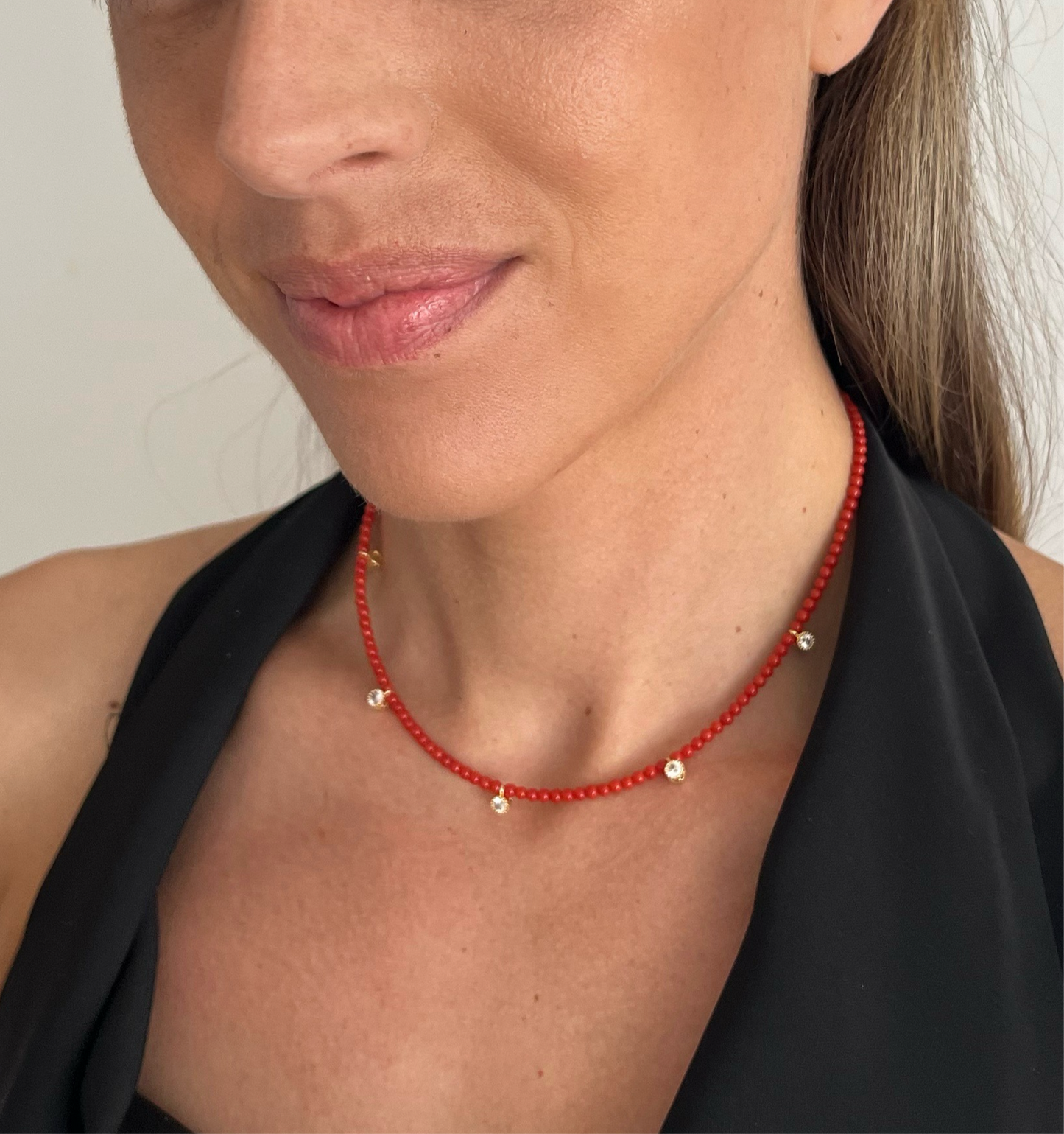 Ce collier fin et raffiné, entièrement fait à la main, se compose de perles de corail rouge de Méditerranée et de petits pendentifs sertis de cristaux étincelants. L’association du rouge vif des perles et des détails dorés offre une touche d’élégance discrète.
