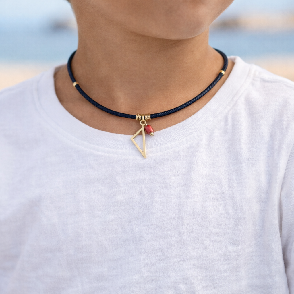 Collier enfant Isula porté avec cordon noir, pendentif Corse doré et tube de Corail rouge de Méditerranée