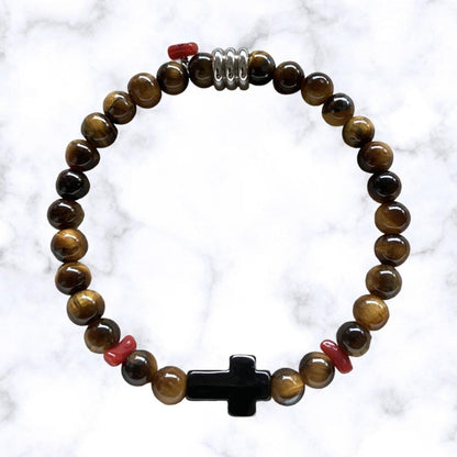Bracelet élastique en perles Œil de Tigre aux nuances brunes mordorées. Au centre une croix noire en acier inoxydable entourée de petits morceaux de corail rouge de Méditerranée.L'œil de Tigre protège des mauvaises énergies, apporte force et courage et aide à réduire le stress.Le Corail protège, porte bonheur et éloigne le mauvais œil