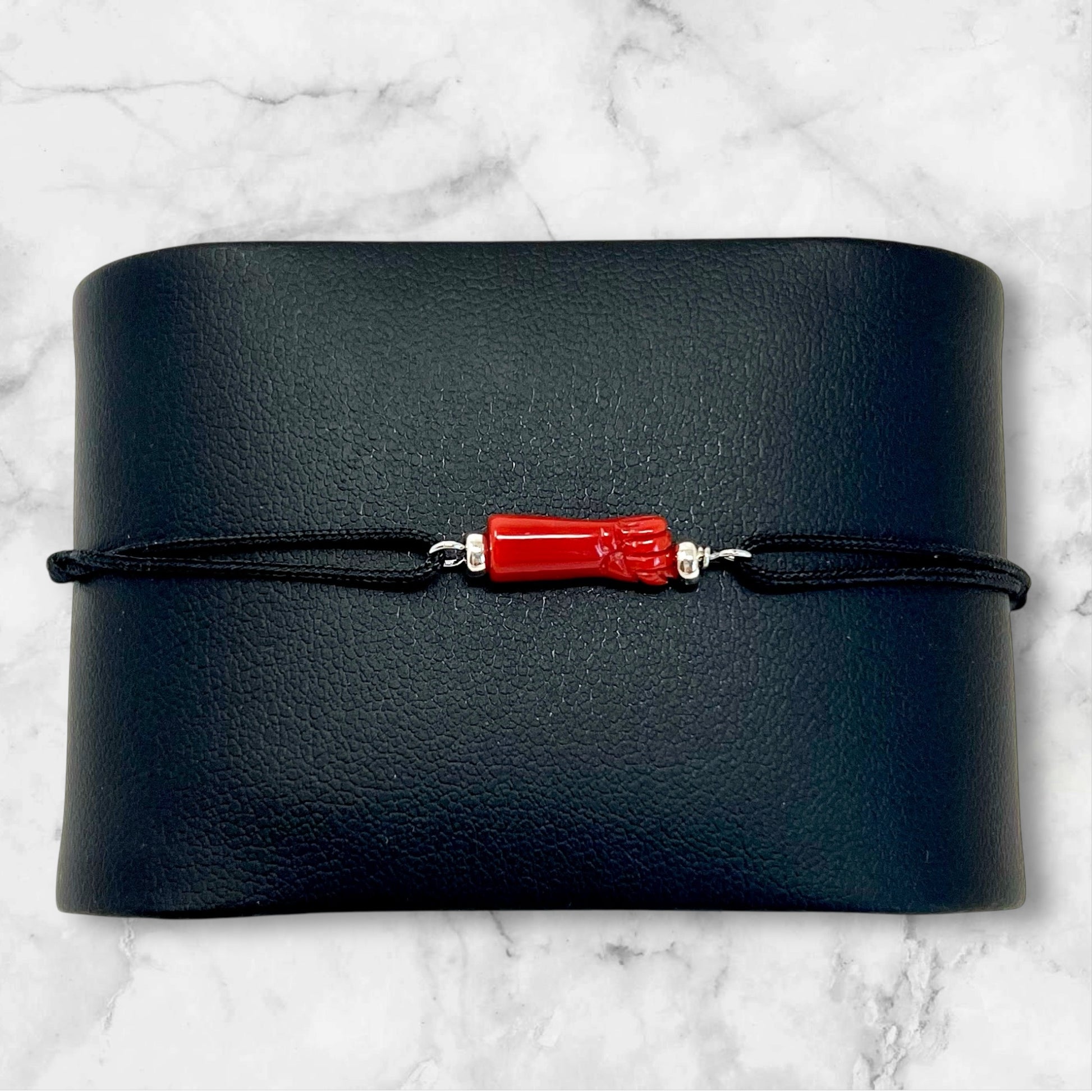 Bracelet ajustable pour homme en cordon noir avec "la main de protection" en corail rouge de Méditerranée.Rondelles en argent 925.Le Corail protège, porte bonheur et éloigne le mauvais œil. Le bracelet est ajustable.