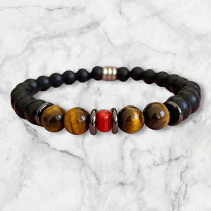 Bracelet élastique en perles d'Onyx noir mat et Œil de Tigre aux nuances brunes mordorées. Au centre un morceau de corail rouge de Méditerranée et rondelles en acier inoxydable.L'Onyx renforce l'estime de soi et la confiance en soi.L'œil de Tigre protège des mauvaises énergies, apporte force et courage et aide à réduire le stress.