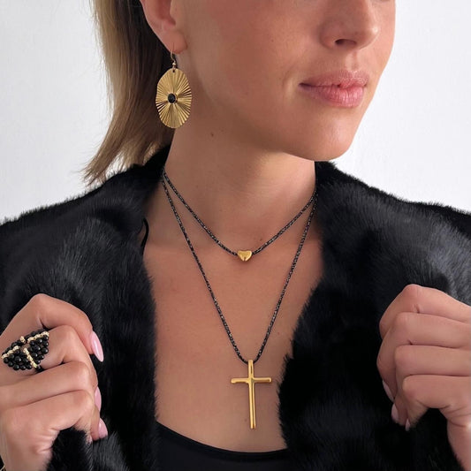 Ce collier double rang sur cordon noir incrusté de fil argenté est orné de pendentifs en acier inoxydable un cœur et une croix.Il est parfait pour un look tendance et moderne.Dimensions :Le collier est réglable grâce à sa chainette d'extension.